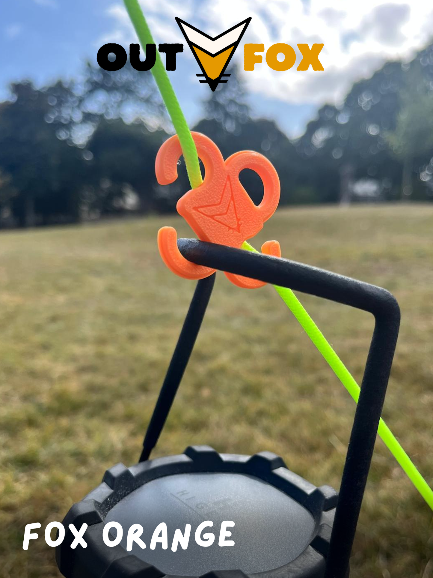 Plastic guy line hook, in Fox Orange, holding a camping lantern in nature with Outfox branding.