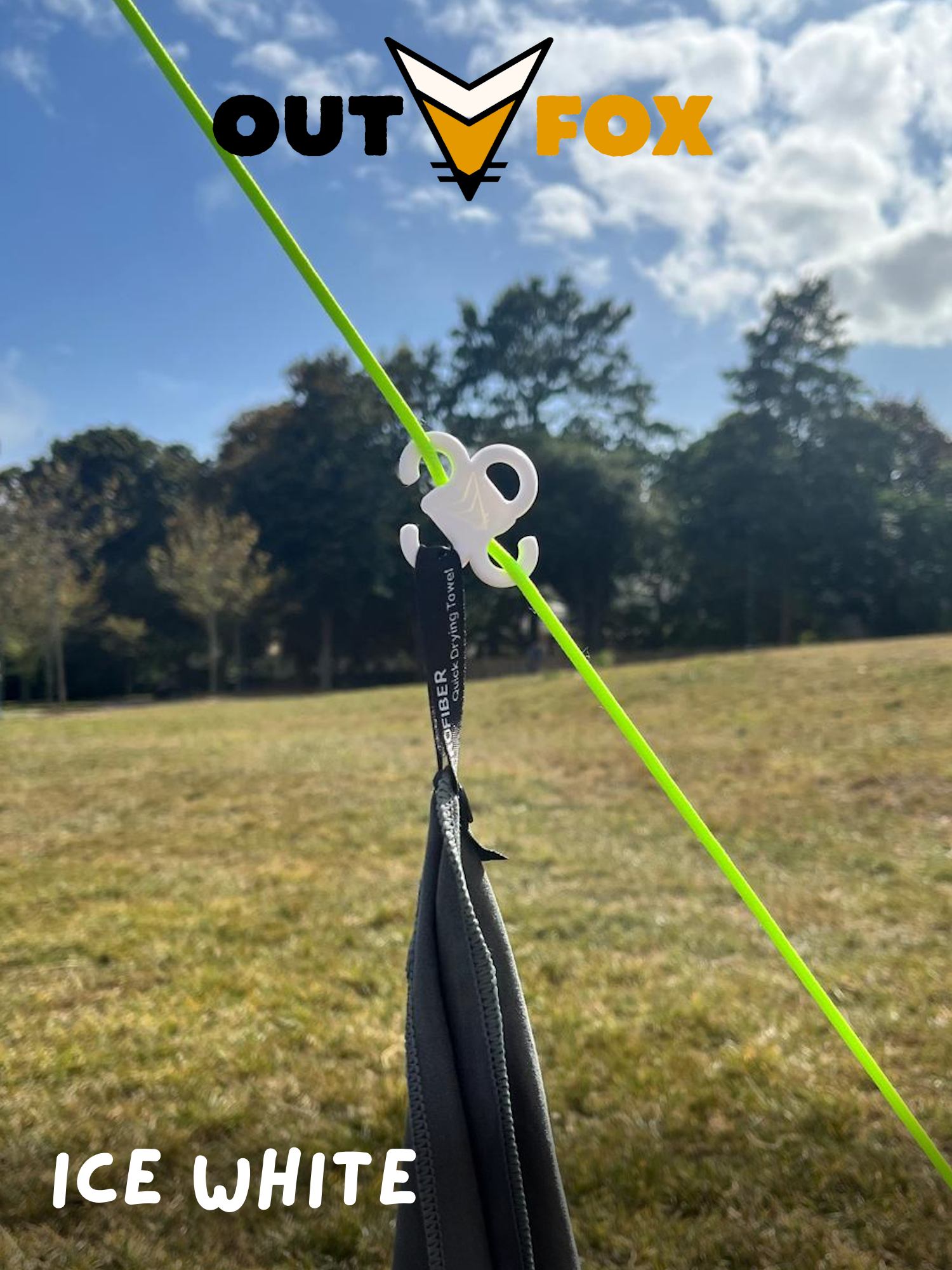 Plastic guy line hook, in Ice White, holding a towel in nature, with Outfox branding.